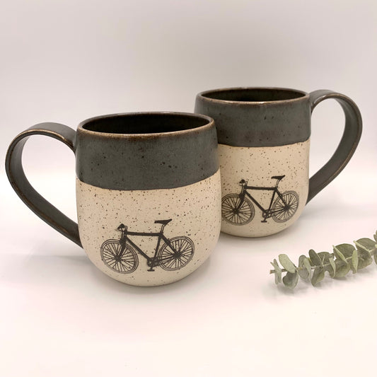 pottery bike mug. The bike is featured on the natural white speckled clay and accented with a dark grey glaze on the handle and rim