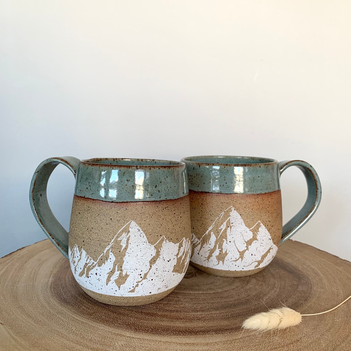 mountain pottery mug - stunning large white mountains are featured on the natural brown speckle clay. Large mountain landscape design wraps around the mug and is accented with a blue-green nature-y glaze on the rim and handle