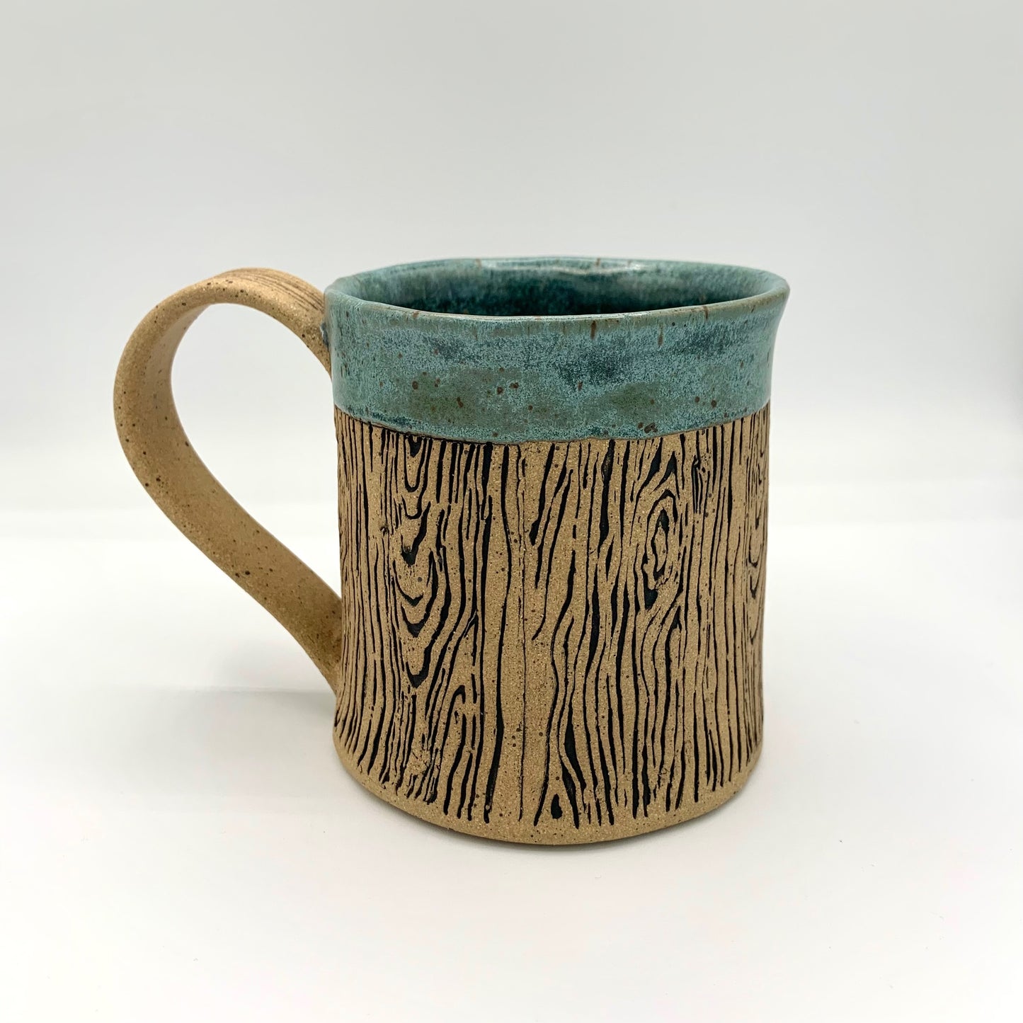 Pottery wood grain mug - a stunning and detailed wood grain design wraps around the body of the natural brown speckle pottery mug. The rim is accented in a blue glaze. Holds 14 oz