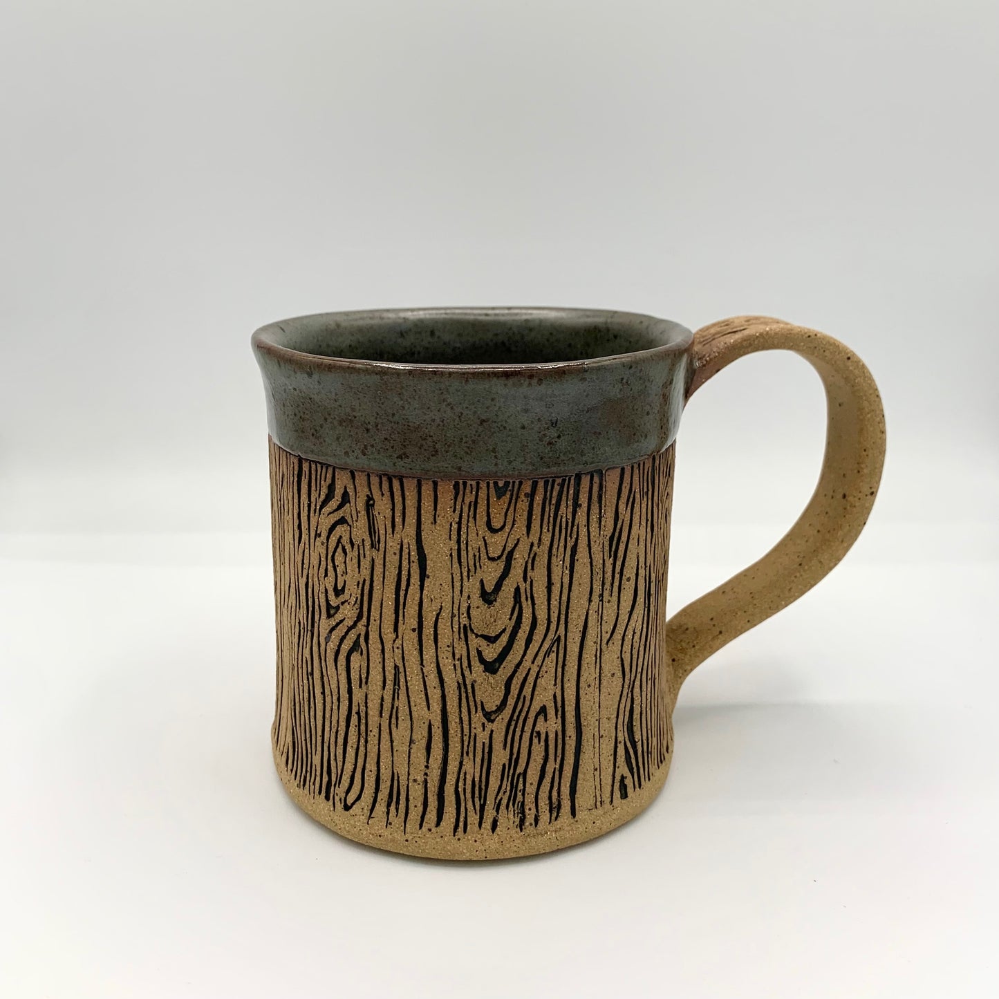 pottery wood grain mug - a stunning and detailed wood grain design wraps around the body of the natural brown speckle pottery mug. The rim is accented with a dark grey glaze. Holds 14 oz