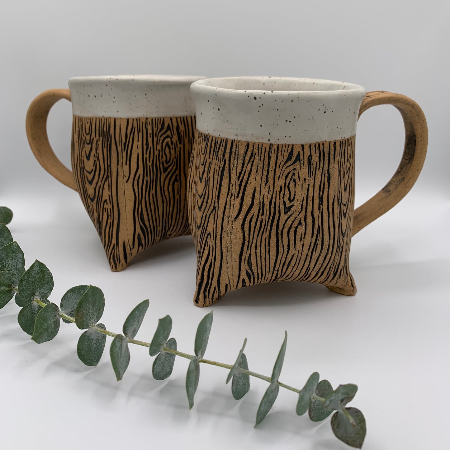 Pottery wood grain tripod mug - a stunning and detailed wood grain design wraps around the natural brown speckle pottery mug. Instead of a flat bottom, this whimsical and unique mug has a sturdy base and sits on 3 feet. The rim is accented in a soft white matte glaze. Holds 12 oz